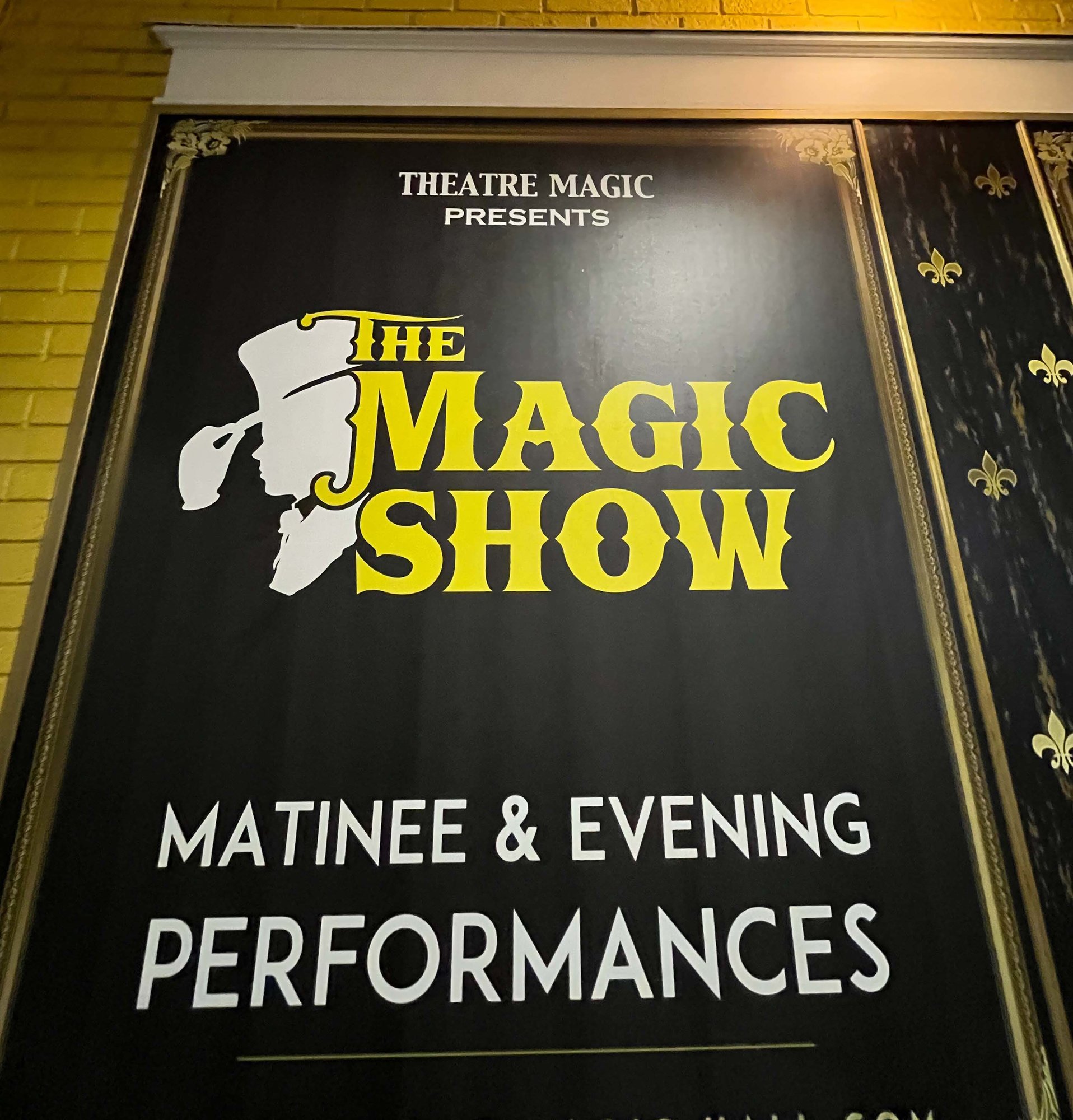 black sign with yellow and white text saying the magic show